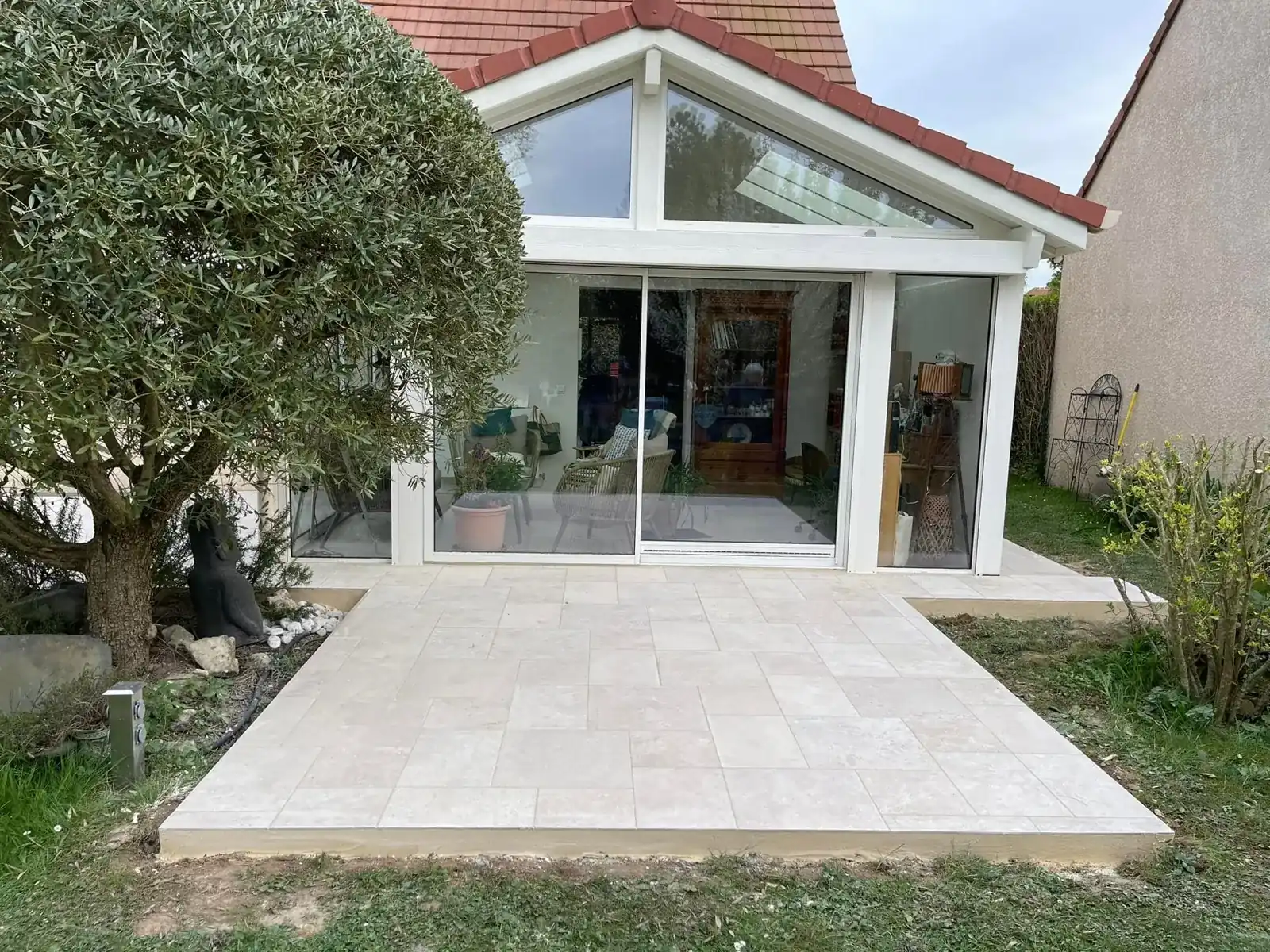 Extension vitrée finie donnant sur le jardin, avec sa terrasse en dalles claires