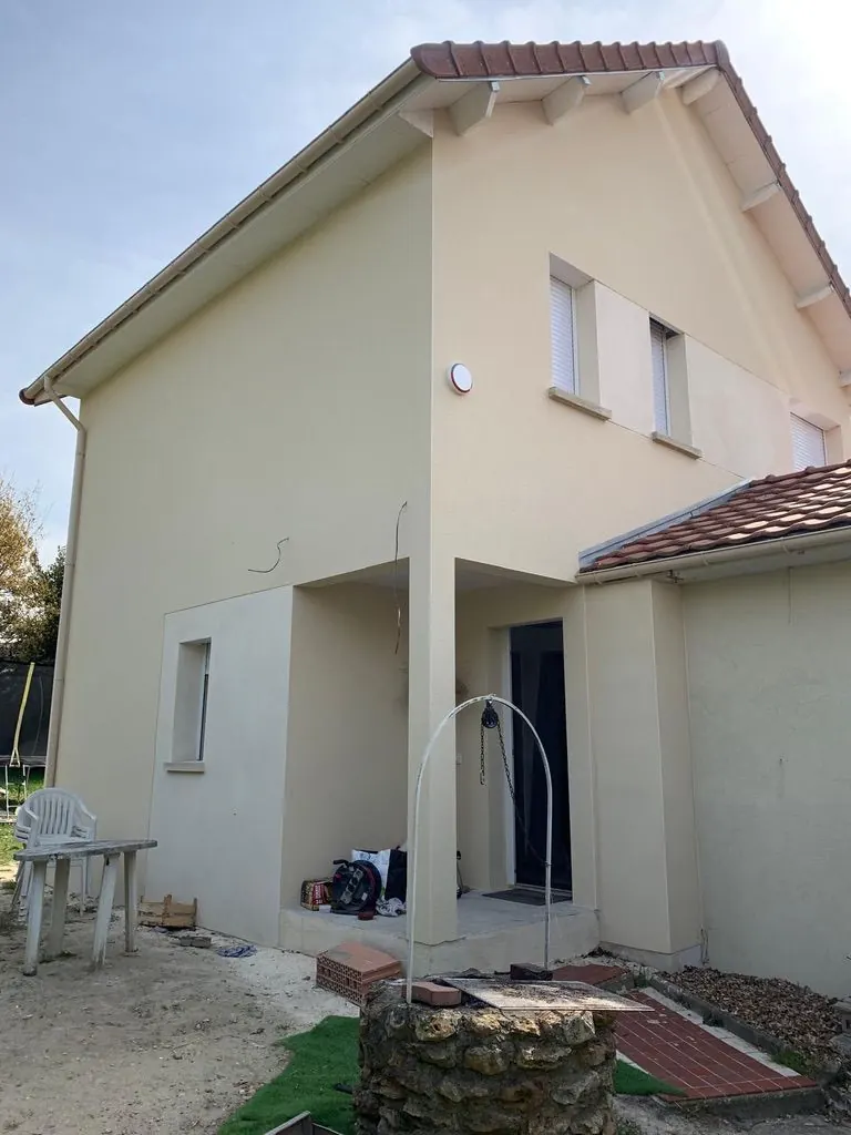 Maison rénovée, façade enduite claire et auvent sur l’entrée