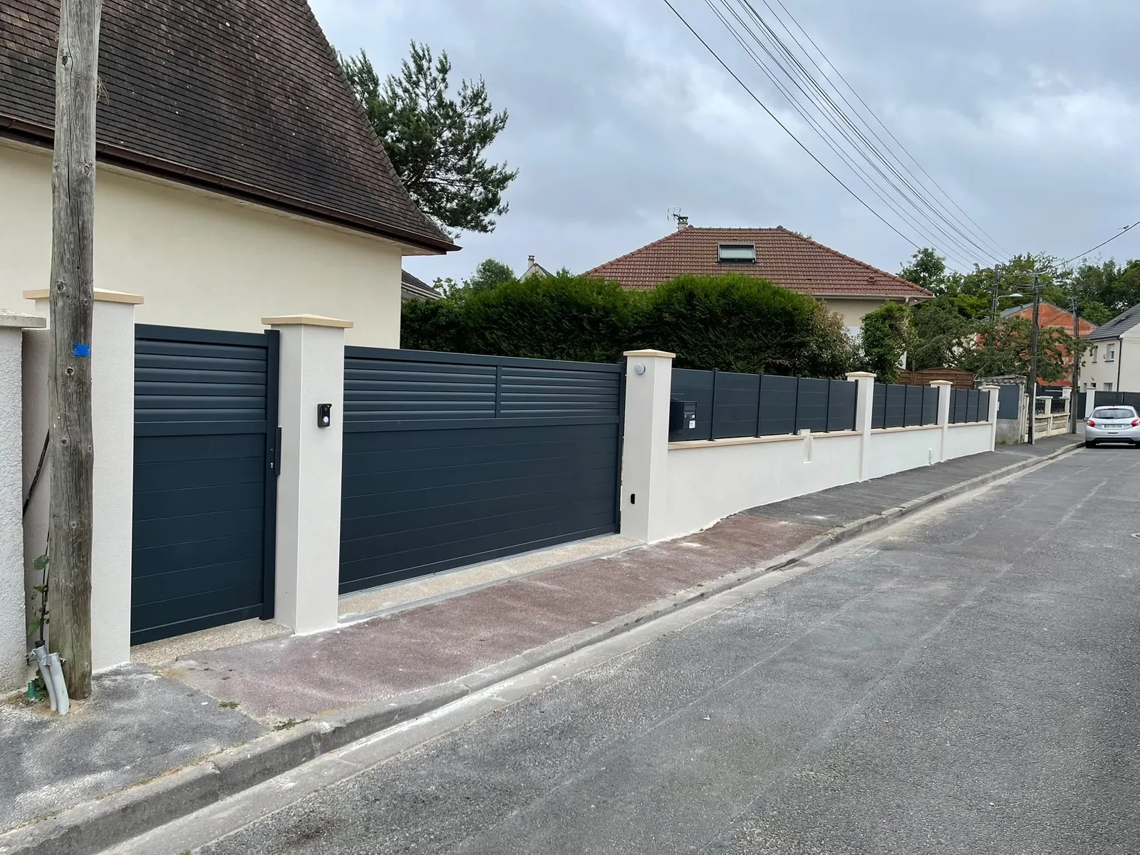 La même entrée finie : portails et clôture aluminium, piliers et mur enduits